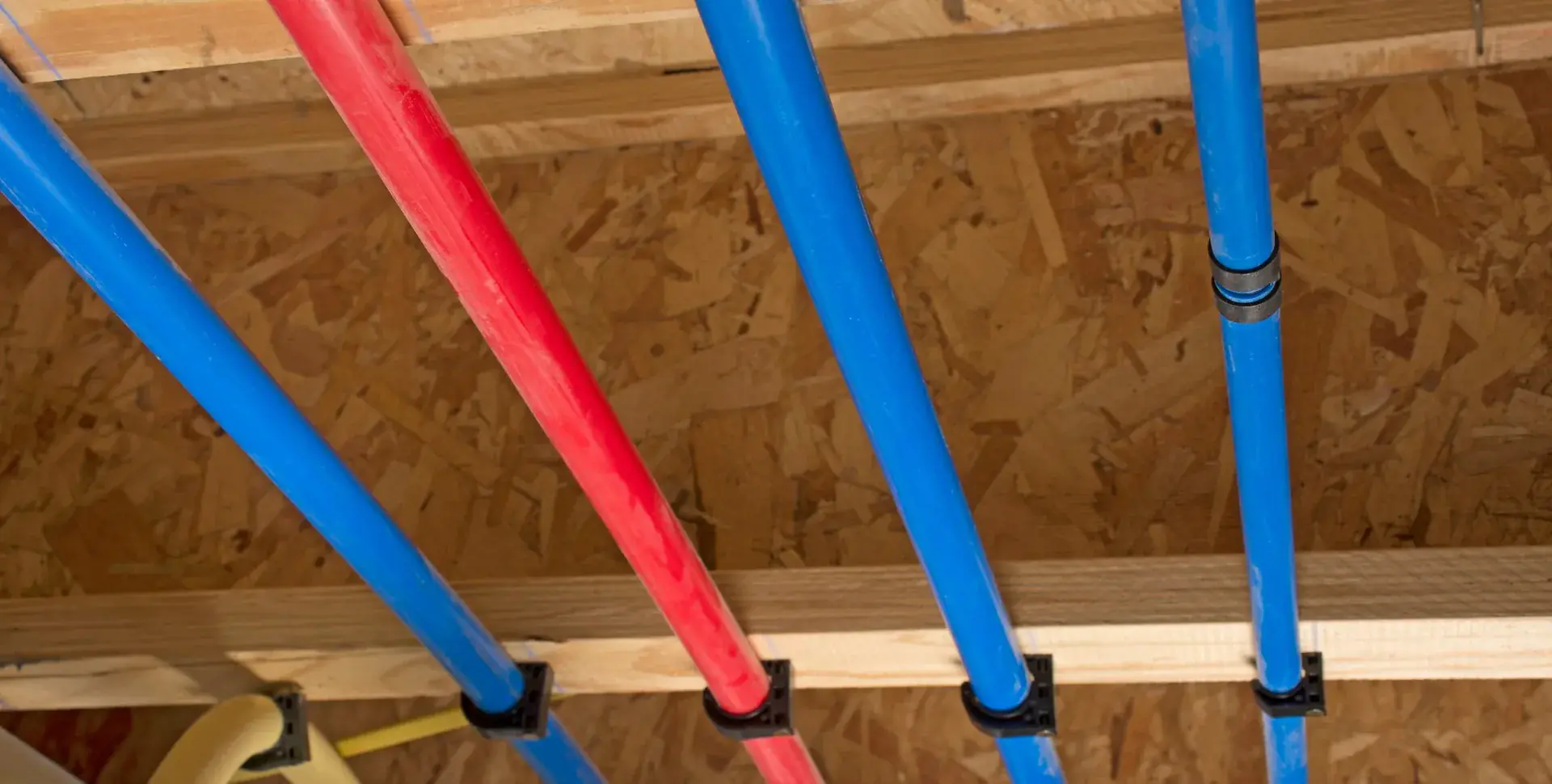 New red and blue PEX supply lines run through the joists during a repipe